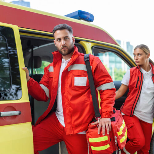 Paramedic nurse and emergency doctor at ambulance with kit. a paramedic, standing at the rear of an ambulance, by the open doors.